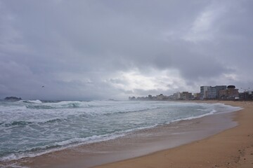 Misty morning at a Korean beach, with waves crashing under a moody gray sky