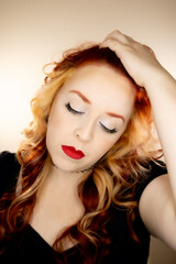 Fototapeta premium Model with red hair and some blonde highlights. Red lipstick and green eyes.