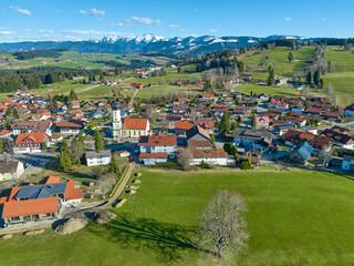 aerial view of the village of Oberreute in earla spring with snowcapped Nagelfluh mountain chain in...