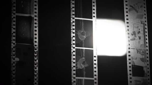 Developing photos in a photography studio. Old school black and white photo film negatives hanging under strong light