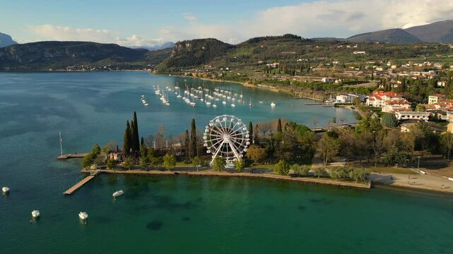 drone aerial video of an iron white ferris wheel  with scenic view to Italian Garda lake Bardolino in sunny day 