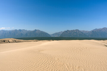 Chara sands and Kodar mountain range. Siberian desert surrounded by mountains. Summer natural unusual landscape.