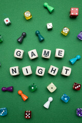 Word dice showing the phrase 'Game Night' with a selection of colourful dice and game tokens lying...