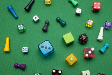 Colorful dice and game tokens lying on a green baize cloth.