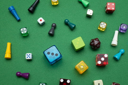 Colorful dice and game tokens lying on a green baize cloth.