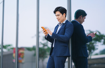 image of a young asian businessman  using phone on the street