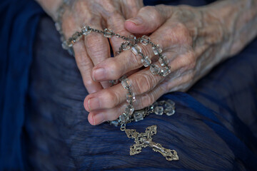 Elderly hands holding a rosary, reflecting faith and tradition during a quiet moment of prayer