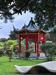 Japanese-style red gazebo in a park among green plants