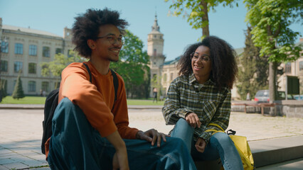 Two African American ethnic friendly students multiracial friends African American woman girl female girlfriend with boy man guy boyfriend in city talking communicate smiling university college study
