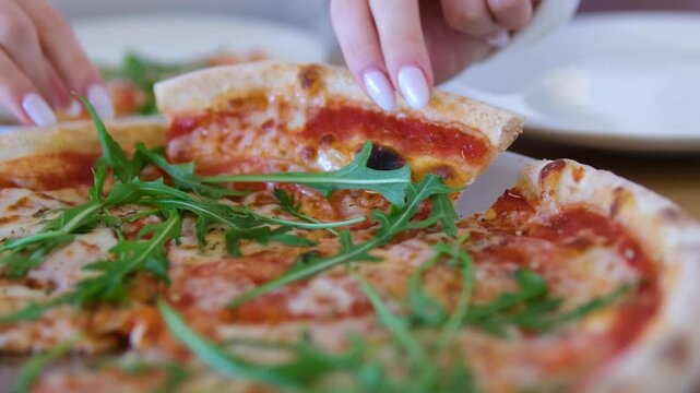 Pizza arugula hand Drizzling Extra Virgin Olive Oil on top of a Pizza