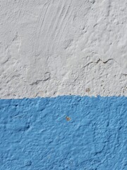 Texture of a painted wall featuring white and blue hues in an urban setting