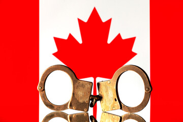 Steel handcuffs against the background of the Canadian flag