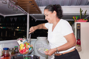 A hispanic brunette woman adding candy with a pair of scissors to a cocktail in Yaguara, Huila, Colombia. Concept of work and entrepreneurship