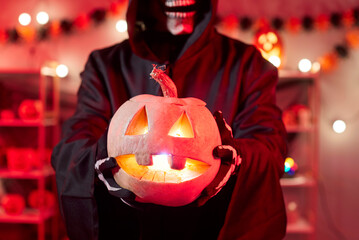 Close-up of the horrible grim reaper monster holding a pumpkin during a halloween party....