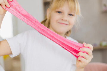 Adorable little girl holding a slime toy, a popular homemade toy all over the world. A child plays...
