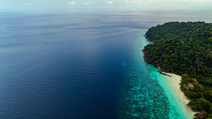 Stunning aerial view of the Surin Islands coastline with its lush green forests, coral reefs and deep blue waters filled with coral and a variety of fish, making it a popular destination for divers