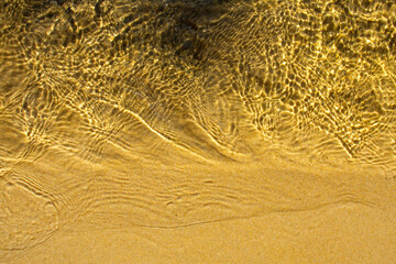 Closeup of sand on the beach with moving water from the sea.