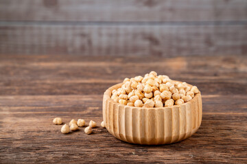 Roasted hazelnuts in bowl on wooden badckground.