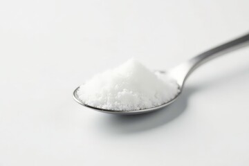 Single spoon of white sugar against white backdrop, still life, close-up