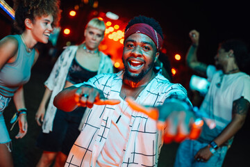 Young man dancing and pointing at music festival with friends