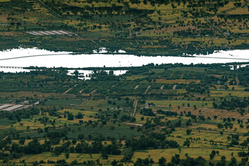 Aerial View of the Landscape: Captivating aerial shot of a vast landscape, featuring a meandering river, verdant fields, and scattered vegetation.