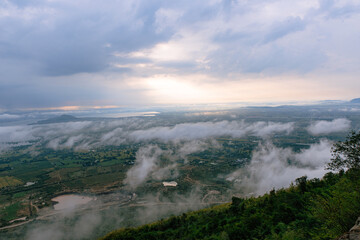 Elevated Vista: Dramatic clouds cascade over a verdant landscape, a scene of majestic beauty.