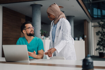 Doctors discussing patient data using laptop in hospital meeting