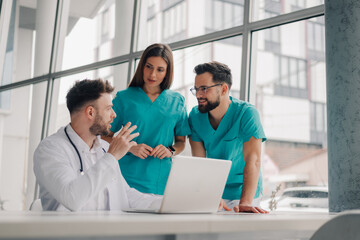 Medical team discussing patient data on laptop in hospital