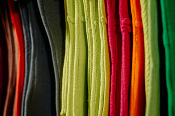 A row of vibrant wool fabrics in unique solid colors, neatly hung to showcase rich fibers and a variety of hues in a clean, organized display.