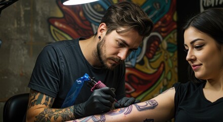 Obraz premium Tattoo artist meticulously inking a design on a client's arm in a vibrant studio with artistic murals