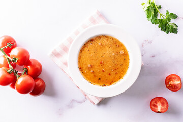 Aromatic spicy cream soup with tomatoes on white marble table top view. Healhy vegan food concept.
