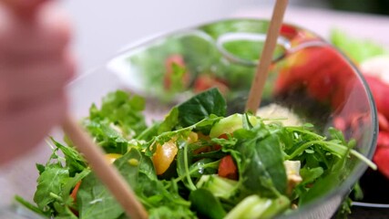 Fresh salad with lettuce leaves and tomato falling into bowl, served with healthy food ingredients on white table, slow motion