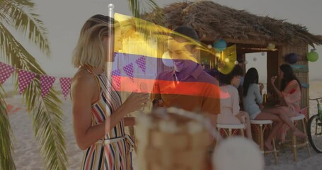 At beach party, two people drinking with Colombian flag animation overlay - Powered by Adobe