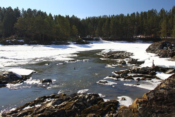 Winter landscape with snow-covered forest and river in the Altai mountains. Manzherok is a rural...