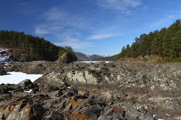 Winter landscape with snow-covered forest and river in the Altai mountains. Manzherok is a rural...