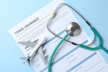Medical tourism. Travel insurance application form, stethoscope and plane model on light blue...
