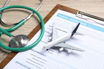 Medical tourism. Travel insurance application form, stethoscope and airplane model on light wooden...
