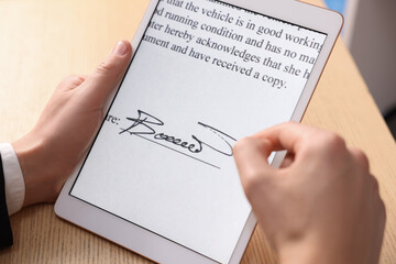 Electronic signature. Man using tablet at wooden table, closeup