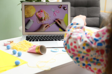 Little girl making handmade toy by following craft tutorial video at home. Child creativity