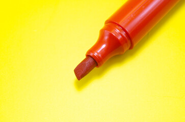 A vibrant red marker poised to create, ready to unleash a burst of color on a sunny yellow...