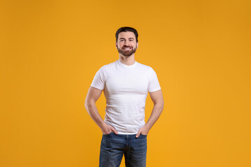 Fototapeta premium Man wearing blank white t-shirt on orange background. Mockup for design