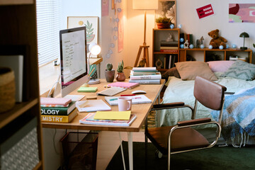 Cozy study area with notebooks, computer, and various plants on a desk. Room features bookshelf, decorations, and soft lighting creating inviting atmosphere