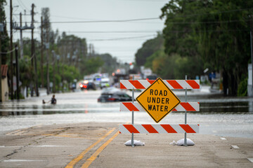 Flooded street in Florida after hurricane rainfall with road closed signs blocking driving of cars....