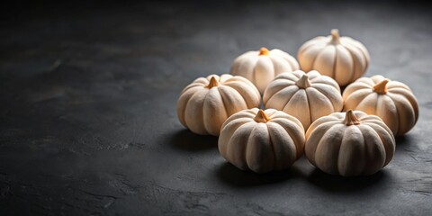 A cluster of creamy white pumpkins arranged on a dark surface