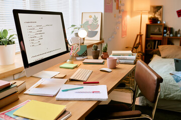 Workspace featuring modern computer, notes, and books, set in cozy home office. Bed and decorative...