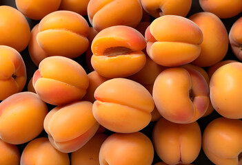 A stack of soft, smooth apricots with their golden-orange skin.