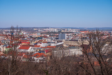 Panoramic view of central Brno, Czech Republic, with churches, rooftops, and distant hills, taken from Spilberk Castle on a sunny spring day.