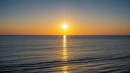 Obraz premium Golden rays of the rising sun creating a starburst effect on calm ocean waters, painting the sky with warm orange and yellow hues for a breathtaking natural view