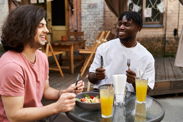 Two handsomely dressed men enjoy a delightful romantic date over brunch at a charming cafe