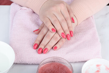 Close-up of woman's hands with manicure on pink towel.